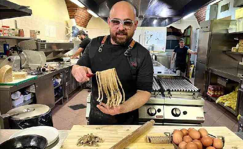 homem segurando macarrofresco em uma cozinha