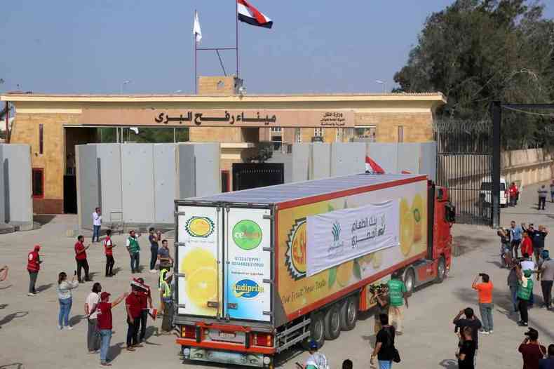 Pessoas no lado egpcio da passagem de fronteira de Rafah observam passagem de comboio de caminhes transportando ajuda humanitria para a Faixa de Gaza 