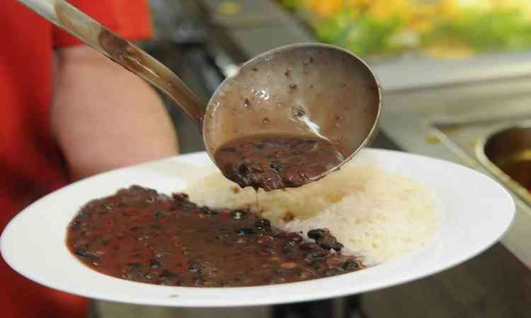 arroz com feijo, mulher colocando mais feijo no prato com a concha 