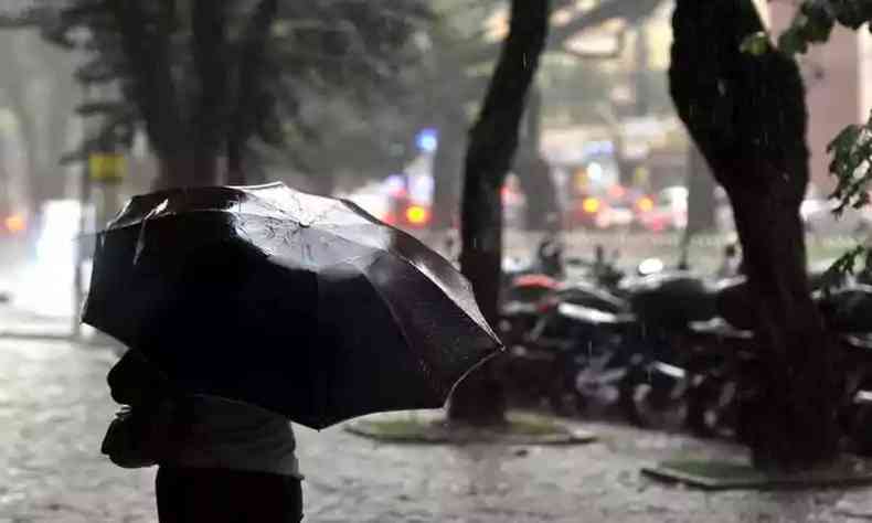 Na foto, pessoa caminha com guarda-chuva, na regio Central de BH