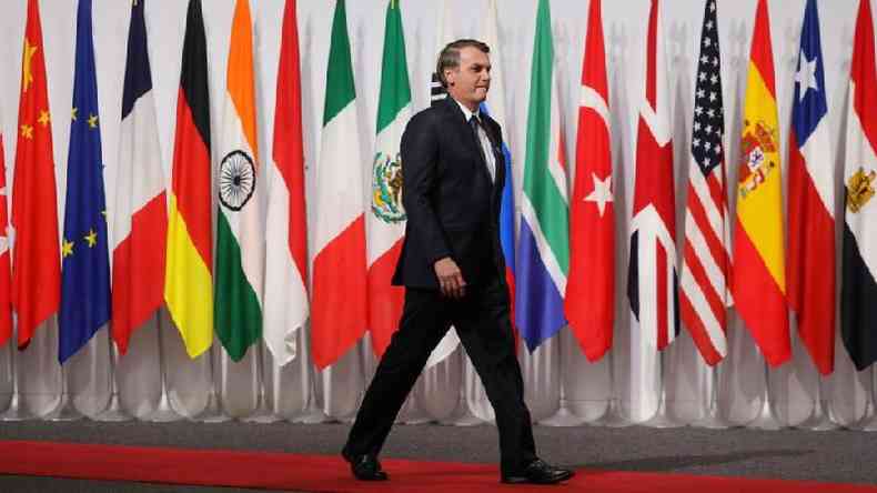 Jair Bolsonaro caminha em frente a bandeiras de pases do G20 durante encontro do grupo em 2019