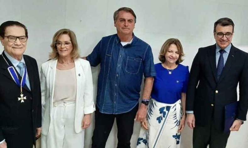 Divaldo Franco recebeu honras de Insígnia da Ordem do Rio Branco por Bolsonaro em julho de 2022(foto: Redes Sociais/Reprodução) Divaldo Franco, um homem branco idoso de cabelos e olhos escuros que usa óculos e terno com a medalha da Ordem do Rio Branco, posa próximo de Jair Bolsonaro, que usa uma camisa azul escuro e calças pretas. Há mais duas mulheres e um homem presentes