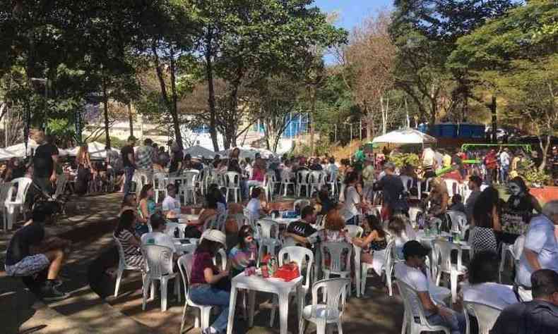 pessoas sentadas em mesas no meio da rua fechada no bairro Santo Agostinho