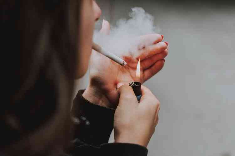 Close seletivo de uma mulher acendendo um cigarro com um isqueiro