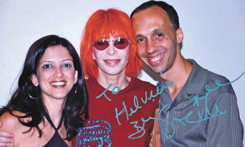 A foto carinhosa de Rita, com autógrafo, ao posar com Helvécio Carlos(foto: Acervo pessoal) Mulher sorridente, Rita Lee, de cabelo vermelho, e Helvecio Carlos sorriem para a câmera
