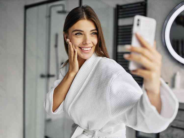 mulher jovem em um roupao de banho tirando uma selfie