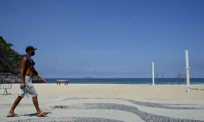 Homem caminha pela praia de Copacabana 