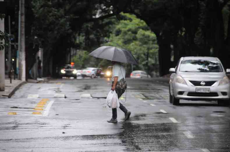 Sr atravessa Av Getlio Cargas e centro. Reflexos de BH, na praa Sete nas poas de gua deixadas pela chuva.