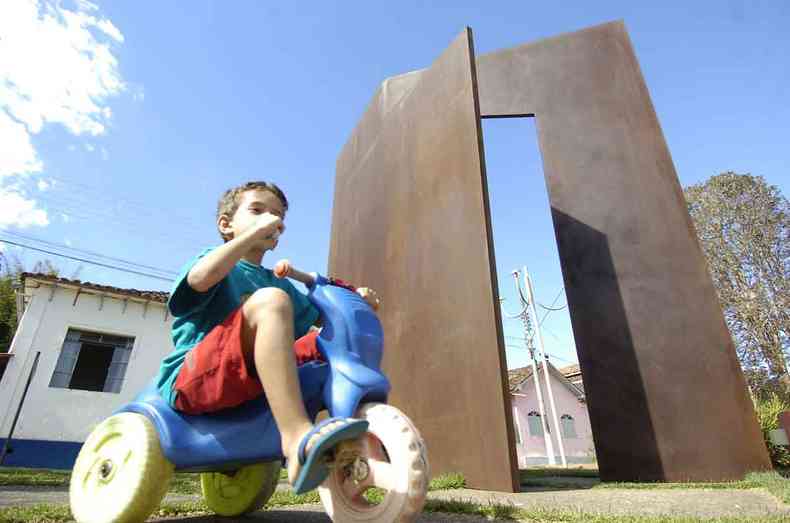 Criana de velocpede passa em frente a escultura de Amlcar de Castro, numa praa da cidade de Dom Silvrio 