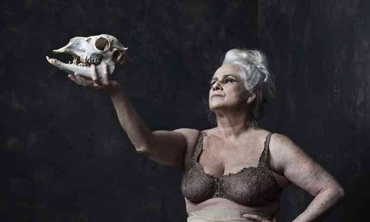 Atriz Vera Holtz, com suti  mostra, segura esqueleto de animal
