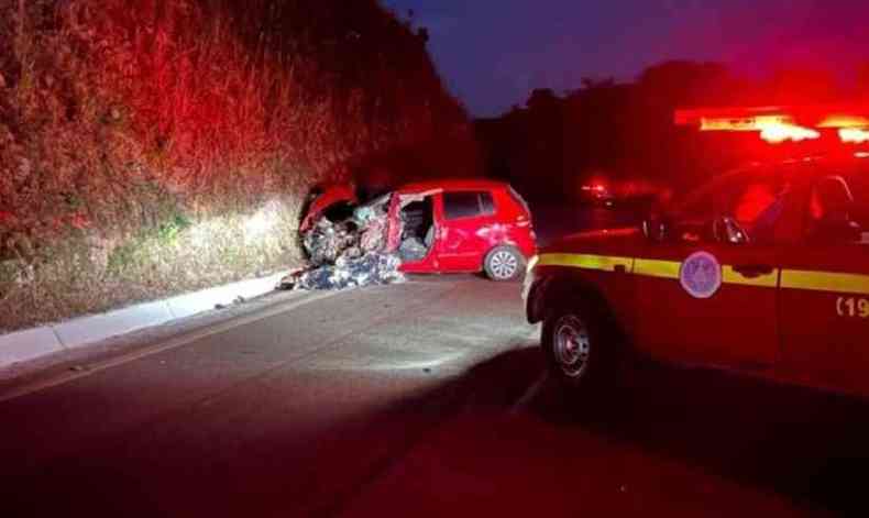 Carro vermelho com a frente destruda, prximo a um barranco. 