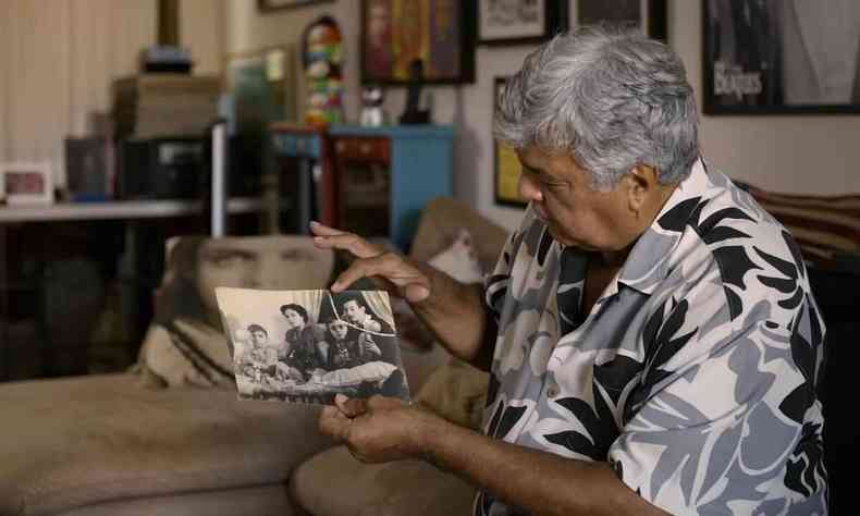 Sentado no sof, Sidney Magal mostra fotos antigas em cena do documentrio 'Me chama que eu vou'