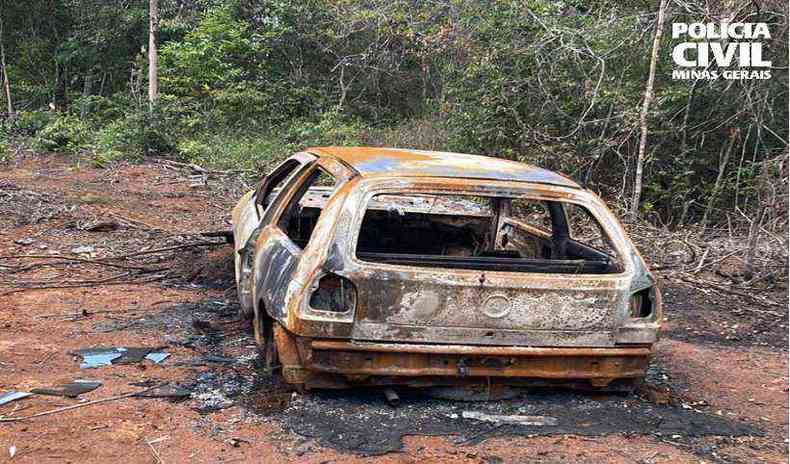 Carro carbonizado em uma estrada de terra