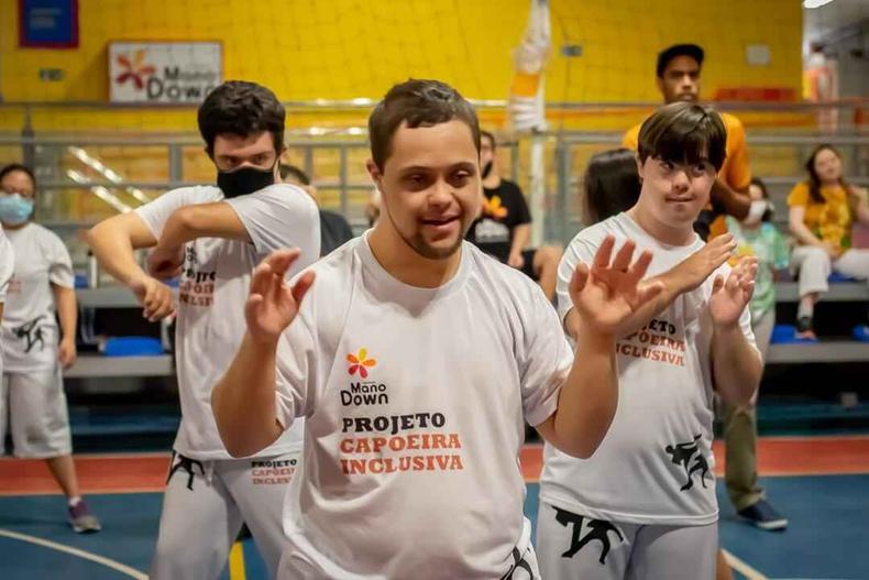Instituto Mano Down realiza diversas ações para pessoas com síndrome de down(foto: Instituto Mano Down/ Divulgação) A imagem mostra três homens com síndrome de down no instituto, eles vestem a camisa do Mano Down e estão praticando atividades em movimento.