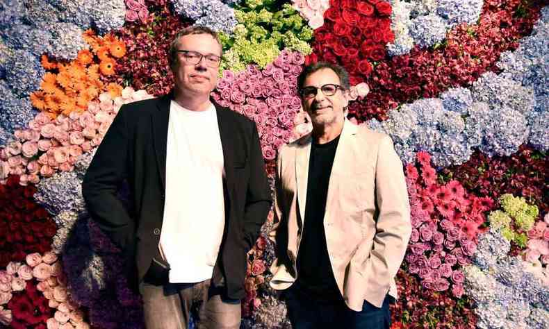 Joo Emanuel Carneiro e Carlos Arajo, autor e diretor da novela Todas as flores, olham para a cmera. Ao fundo, h parede coberta de flores