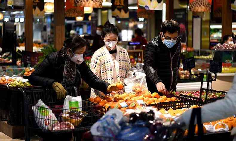 De mscara, moradores fazem compras em mercado de Wuhan, na China(foto: Noel Celis / AFP)