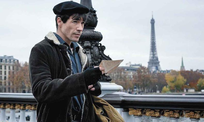 Juan José Ballesta faz o papel de Lucio Urtubia, autor de operação para desestabilizar um dos bancos mais poderosos do mundo (foto: Netflix/reprodução) Ator Juan José Ballesta caminha em Paris, com a Torre Eiffel ao fundo, segurando um papel