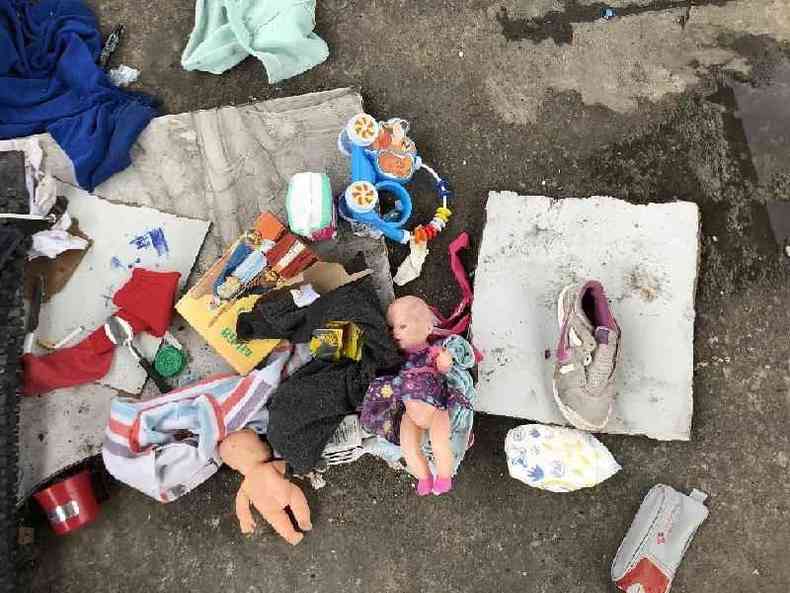 Bonecas, livro, tênis, colher, roupas e outros objetos jogados em chão embaixo de viaduto da zona norte de SP