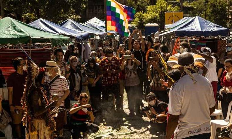 Feira Abya Yala. O local  em uma praa, cercado por vegetao. H vrias barracas organizadas em fileiras e o local est cheio de pessoas