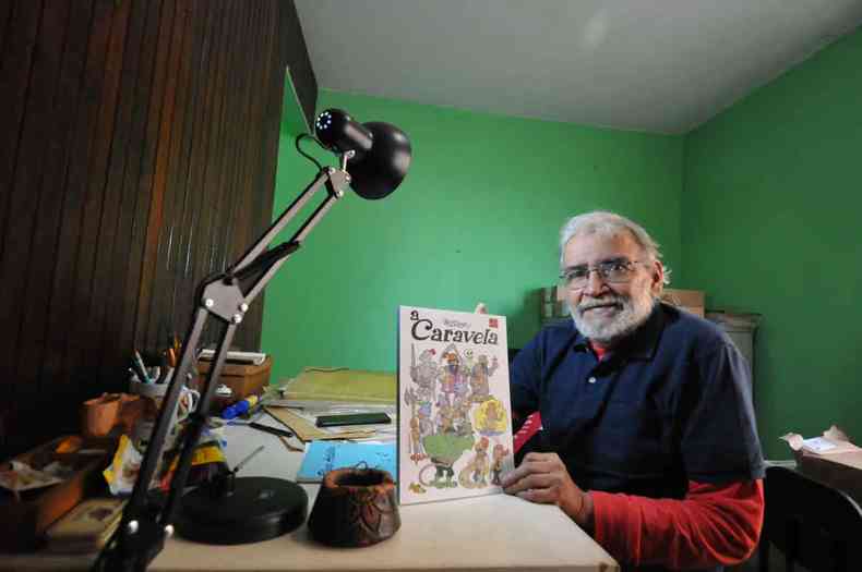 O cartunista Nilson Azevedo, sentado  sua prancheta, exibe edio de a caravela 