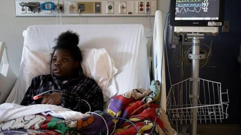 Menina deitada em cama de hospital