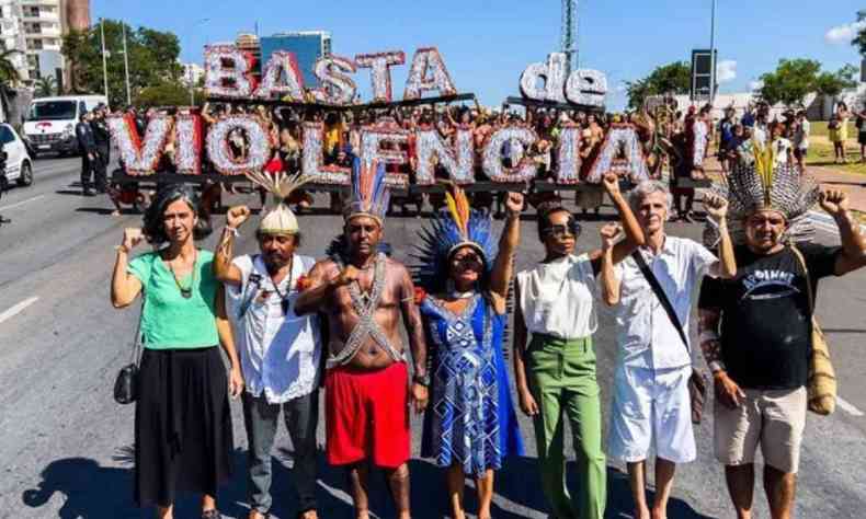 Grupo de representantes dos povos indígenas em frente a letreiro 'Basta de violência'