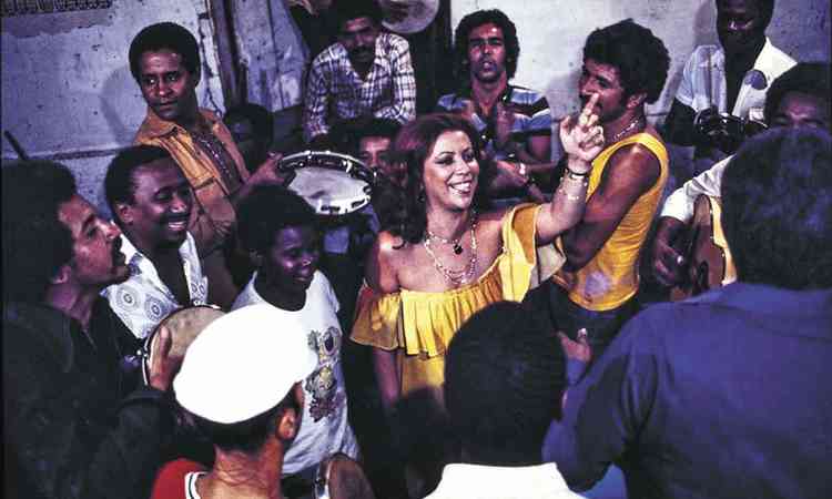 Beth Carvalho, de vestido amarelo, canta em roda de samba
