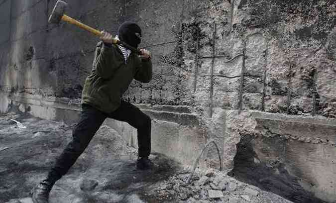 Palestino tenta abrir um buraco no muro que separa Jerusalm, em Israel(foto: Ahmad Gharabli/AFP)