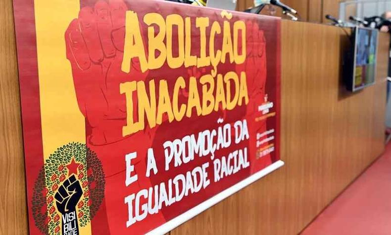 ALMG lançará agenda para criação de Estatuto da Igualdade Racial na terça-feira (30/5)(foto: Luiz Santana/ALMG) Cartaz em auditório da ALMG no qual se lê 'Abolição inacabada e promoção da igualdade racial'