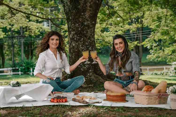 Paula Fernandes e Lauana Ribeiro brindam com copos de suco em piquenique ao ar livre