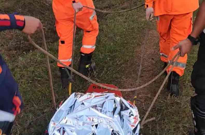 Bombeiros transportam por maca em trilha o corpo de um garoto de 13 anos envolto em manta aluminizada mata trmica em trilha em So Joo Del rei