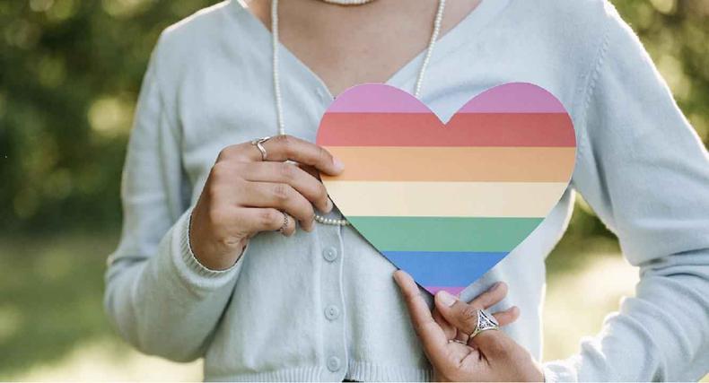 Mulher segura um corao com as cores da bandeira LGBT cobre o prprio peito 