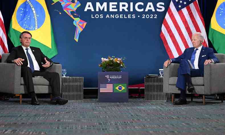 Presidente dos EUA, Joe Biden, sentado; e presidente Jair Bolsonaro falando ao microfone