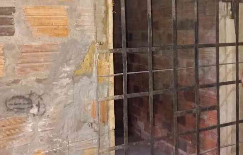 Foto mostra cela de tijolo fechada por uma grade