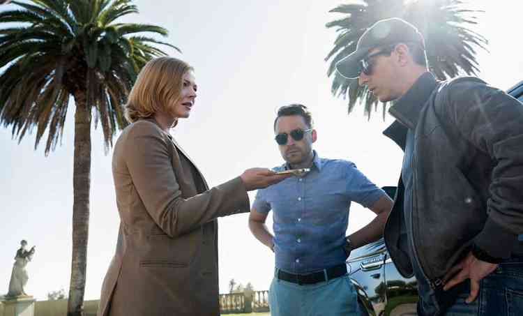 Atriz Sarah Snook entrega celular ao ator Jeremy Strong, observada por Kieran Culkin, em cena da srie Succession
