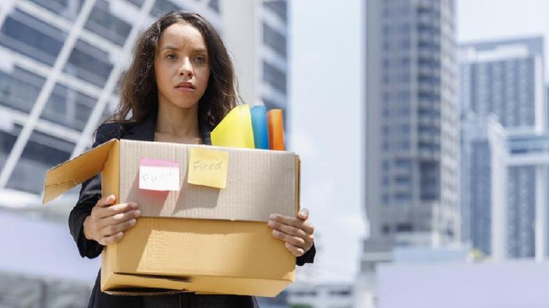 Mulher com uma caixa de pertencentes saindo de um escritrio