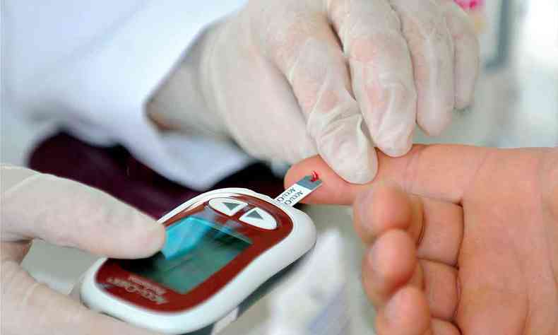 Pofissional da sade mede diabetes, com picada no dedo de paciente