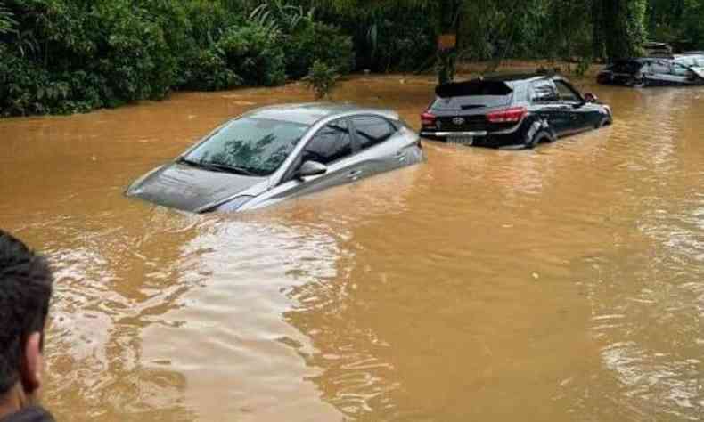 Um carro prata e um preto submersos em gua barrenta