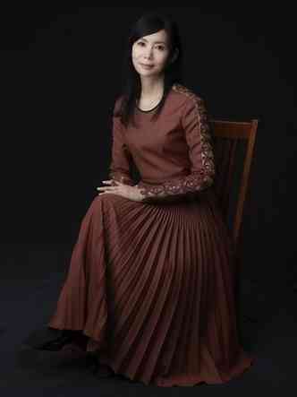 A cantora Mariya Takeuchi olha para a cmera, usando vestido longo e sentada em cenrio com o fundo marrom