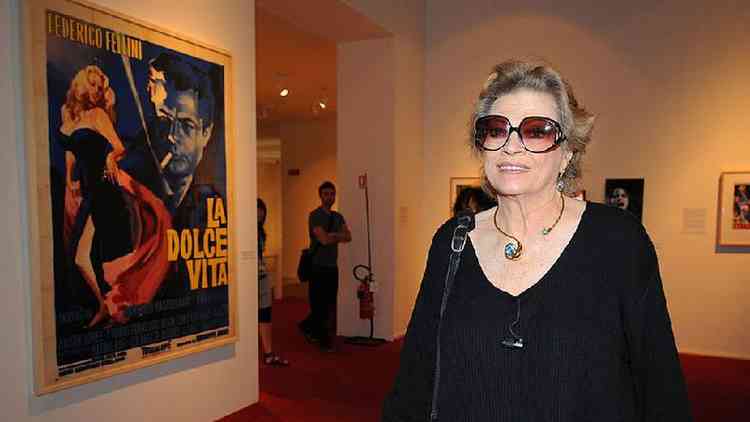 Anita Ekberg em frente a um cartaz de A Doce Vida, em exposio celebrando obra de Federico Fellini