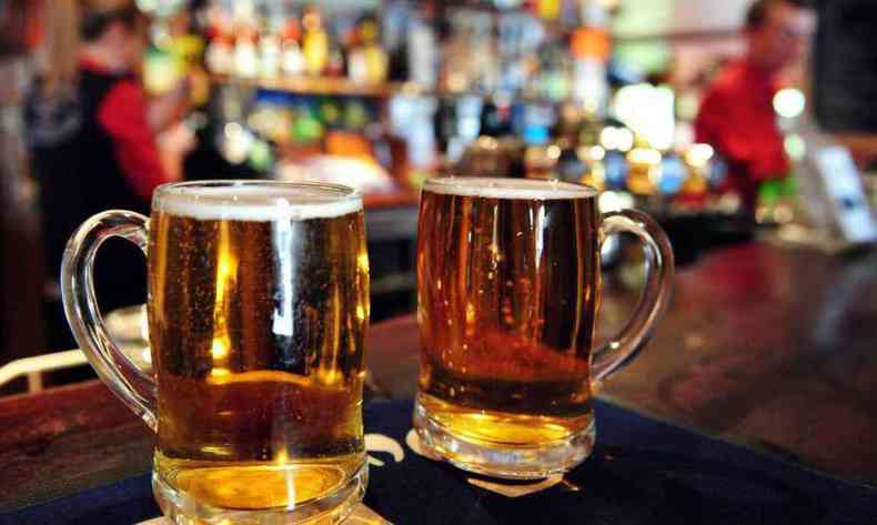 Duas canecas de cerveja em uma bancada de bar.