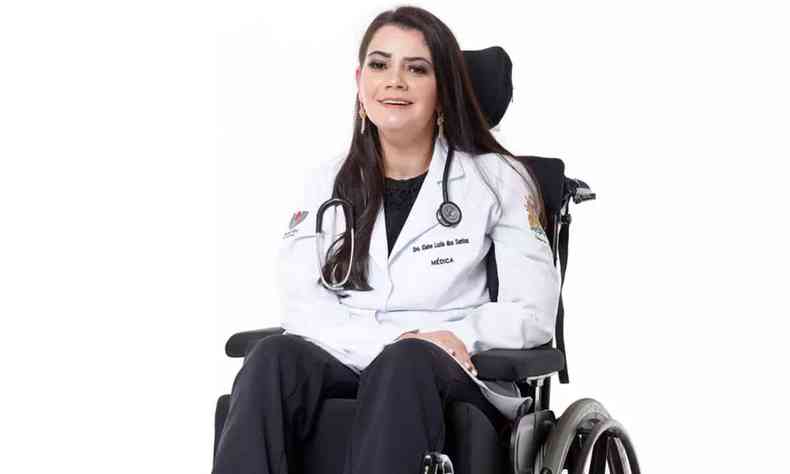 Elaine Luzia dos Santos sentada em uma cadeira de rodas e usando jaleco, em um fundo branco