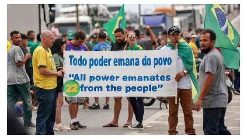 Manifestantes bolsonaristas com cartaz e nmero 22 , vestidos de verde e amarelo, fecham rodovia