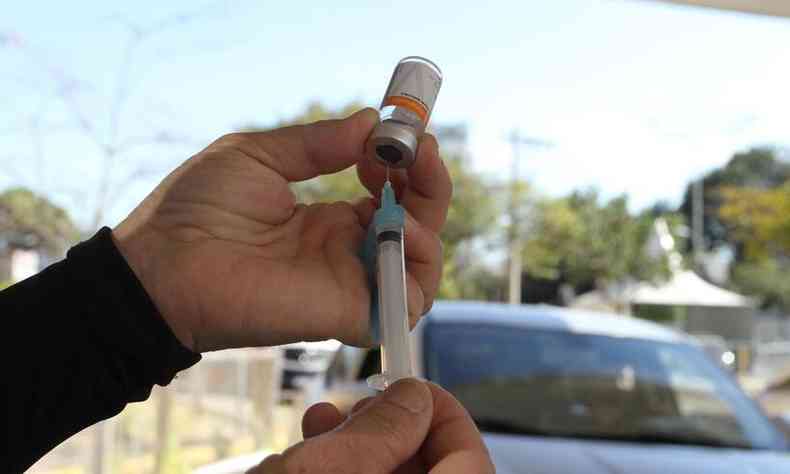 Primeira dose da vacinao para publico com 24 anos. Enfermeira preparando a vacina, frasco e seringa. 