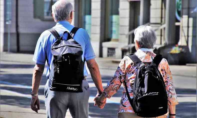 um casal de idosos, de costas, caminhado pela rua