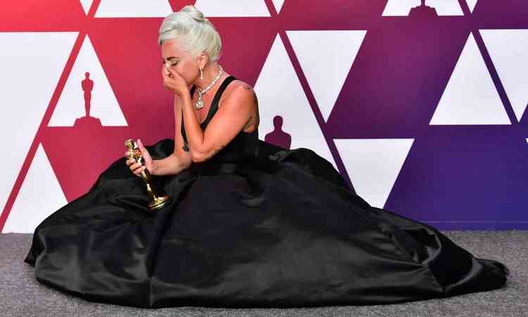 Lady Gaga, segurando o Oscar, chora sentada no cho na cerimnia do prmio realizada em 2019