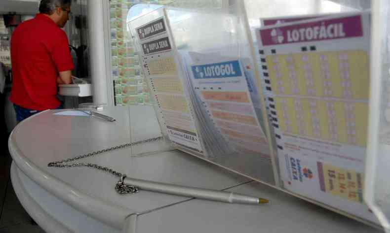 Volantes das loterais lotogol, lotofcil e dupla sena em dispensers de uma casa lotrica.