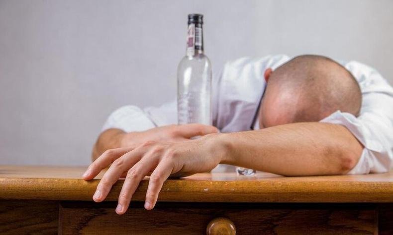Pílula contra a ressaca, agora, tem lista de espera e compra limitada diante da alta procura(foto: Michal Jarmoluk/Pixabay ) homem debruçada na mesa ao lado de uma garrafa de bebida