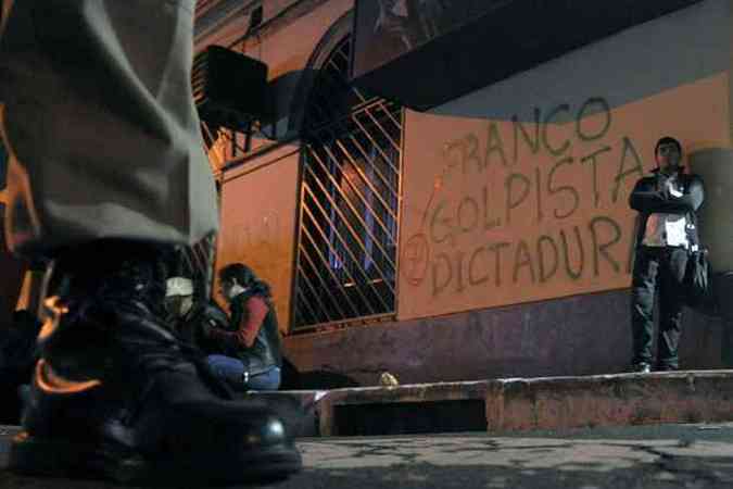 Manifestantes a favor de Fernando Lugo so vigiados em frente a sede da TV estatal em Assuno (foto: NORBERTO DUARTE / AFP)