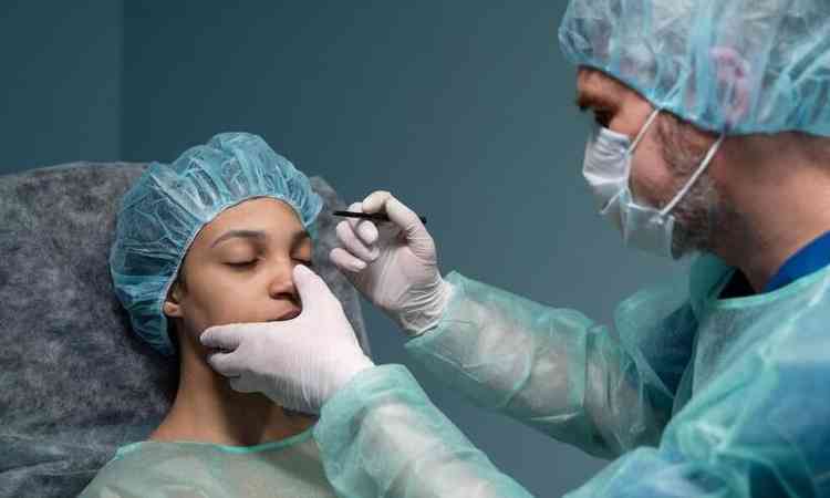 Cirurgio delineando pontos de cirurgia plstica no nariz de uma mulher 
